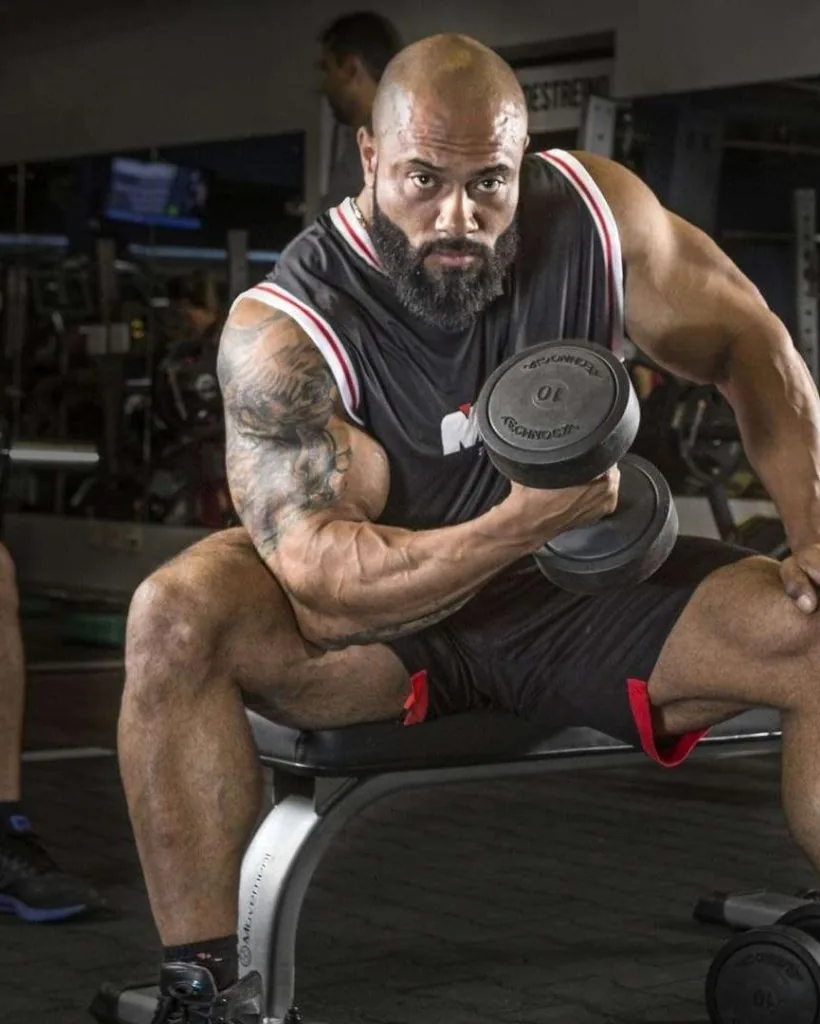 Júlio Balestrin sentado na academia com halter